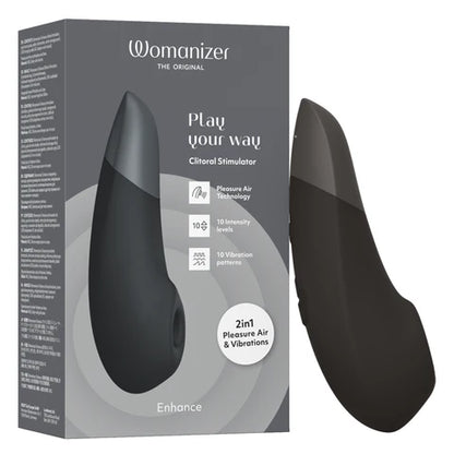 The product image shows the Womanizer Enhance Clitoral Stimulator in black, both the device itself and its packaging are visible. The device has a sleek, curved design and the packaging includes informative text about the product's features.
