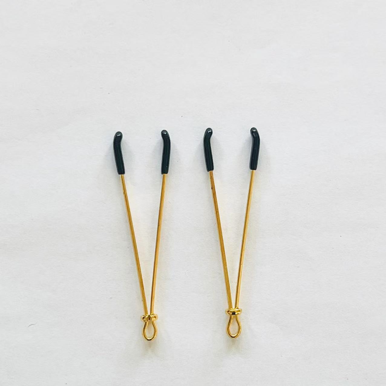 Gold adjustable wire-style nipple clamps with black rubber tips, minimalist BDSM design